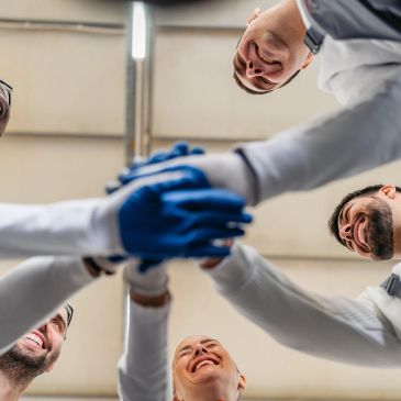 Team members join hands in a circle, symbolizing unity and collaboration.