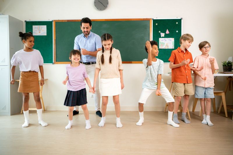 Diverse group of school children enjoying dance activity with teacher in an international classroom, encouraging active learning and teamwork