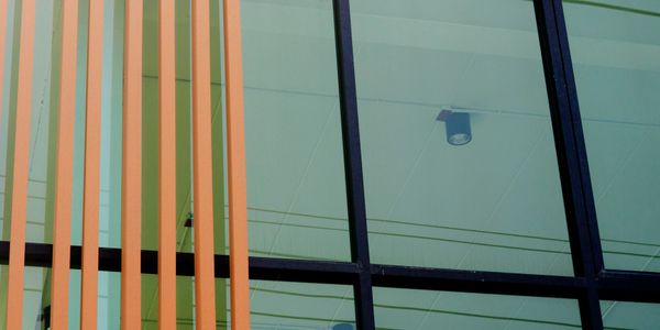 Modern building facade with vertical orange beams and large glass windows.