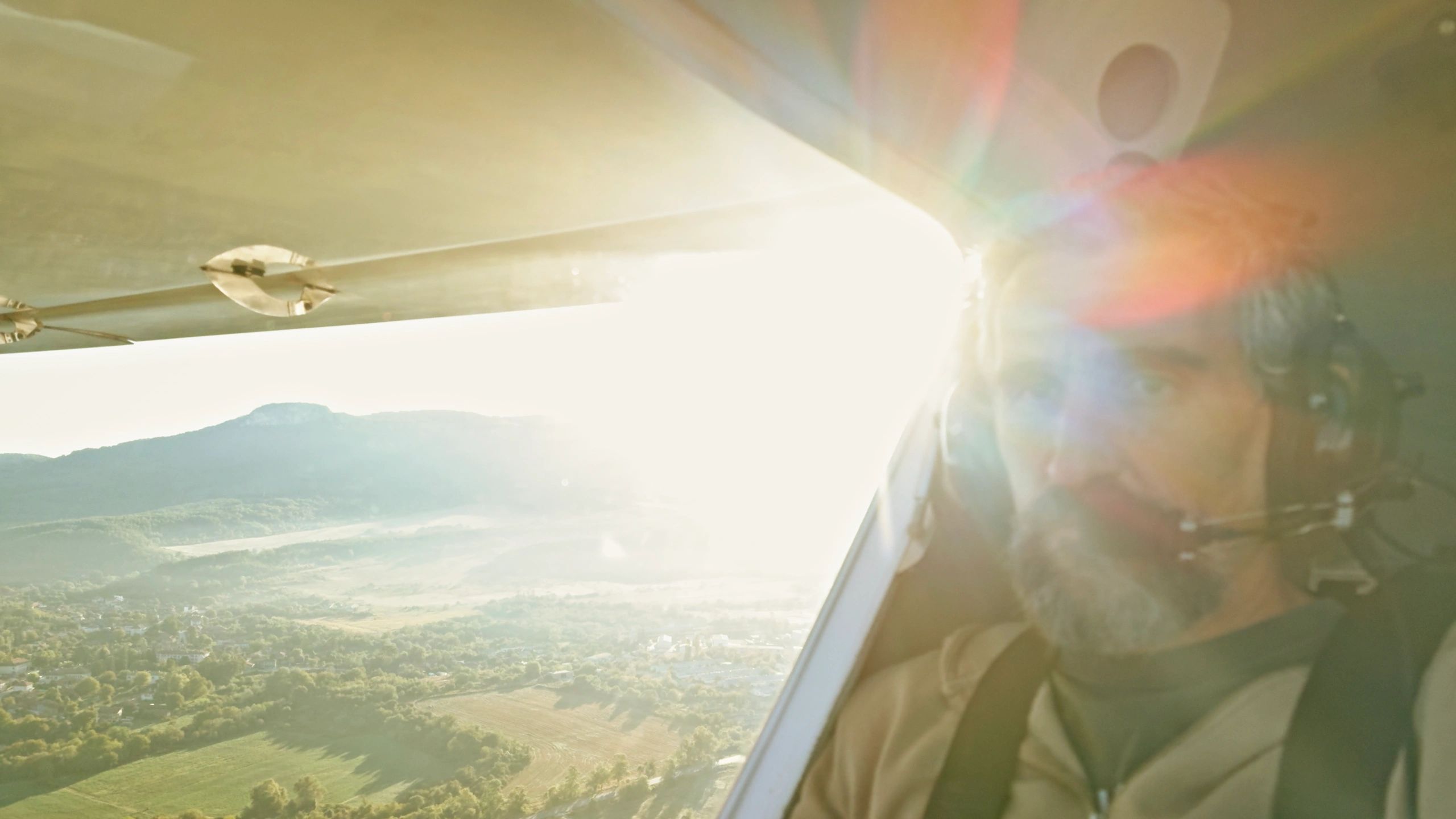 Pilot flying a light aircraft with sun glare through the window.