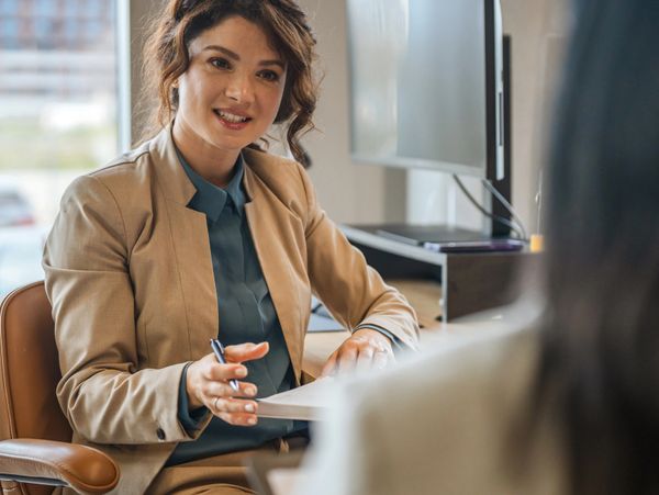 Professional woman in a business suit engaging in a conversation at an office.