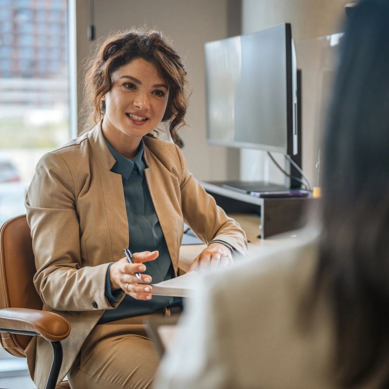 Confident business woman discussing ideas and giving advice to a colleague during a professional meeting in a modern office setup, conveying collaboration and communication