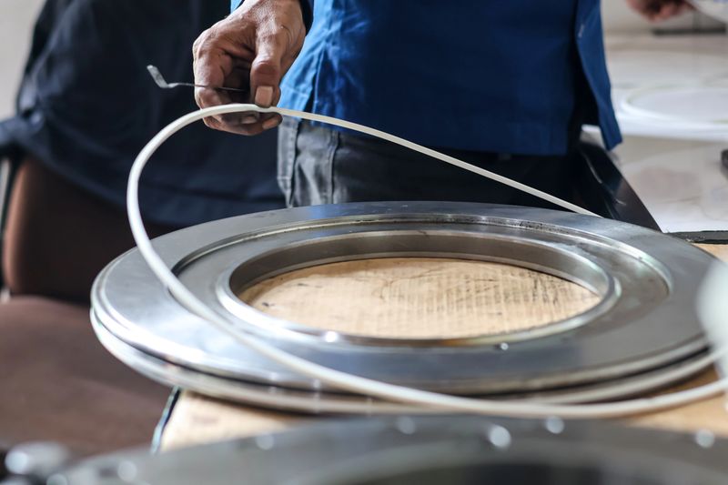 Close up of a mechanic technician hand installing a rubber seal ring onto a large metal automatic transmission piston during assembly in a professional workshop garage.