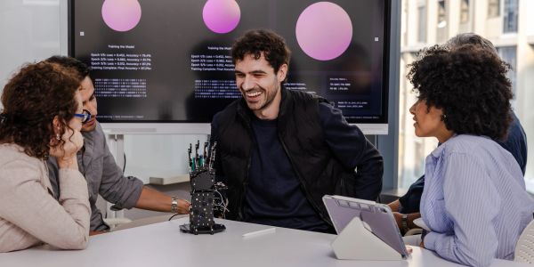 Group discussing robotics with a robot hand at a table.