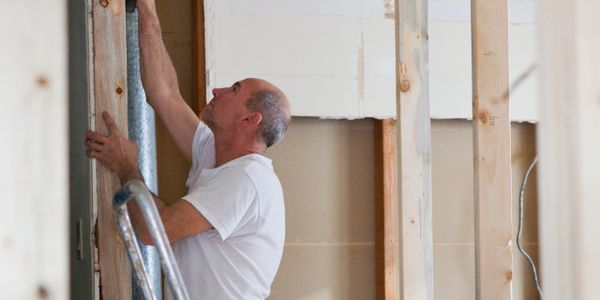 A man working on home renovation, installing drywall or insulation.