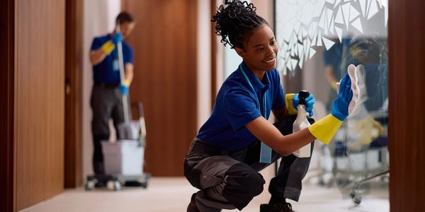 Two janitors cleaning office windows and floor.