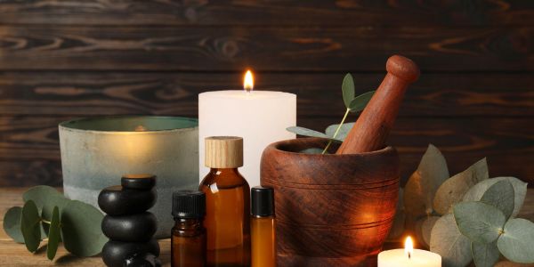 Aromatherapy setup with candles, essential oils, and a wooden mortar and pestle.