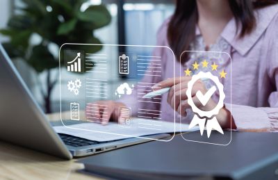 Businesswoman working on a laptop with digital quality icons.