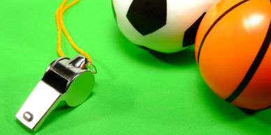 A whistle with soccer and basketball on a green surface.