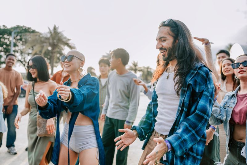 Asian Friends dance and enjoy a lively outdoor concert and music festival gathering with candid movement and youthful social energy, Bangkok