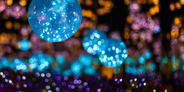Blue glowing balloons among colorful blurred lights.