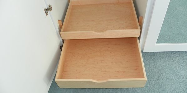 Two empty wooden pull-out drawers inside a cabinet.
