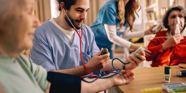 Healthcare workers checking elderly patients' vitals in a care facility.