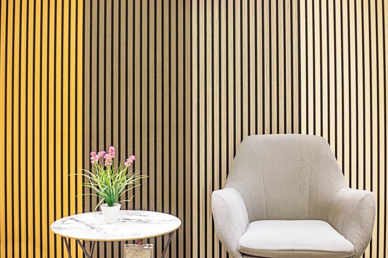 A gray armchair with pink flowers on a table against a backdrop of modern wood trim in an interior