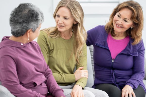 Three women engaged in a friendly conversation.