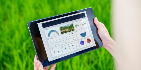 Tablet displaying agricultural data analytics in a green field.