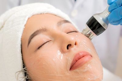 Woman receiving a facial treatment with a skincare device.