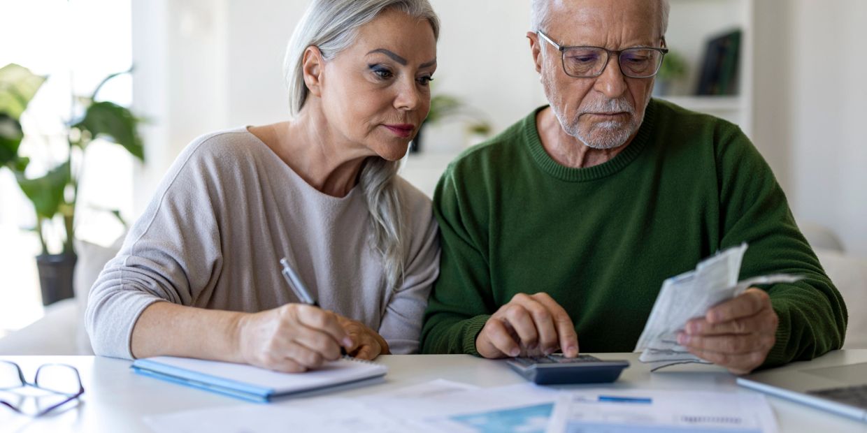 Elderly couple managing finances together at home.