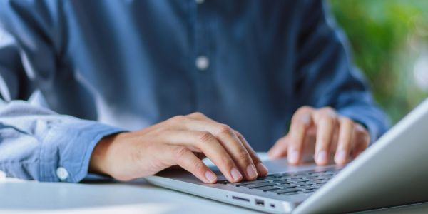 Person typing on a laptop keyboard.