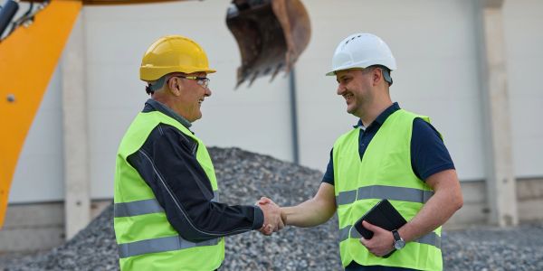 Two construction workers shaking hands at a site.