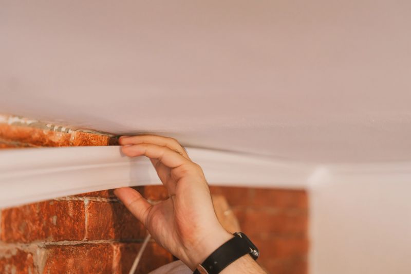 Close up applying construction adhesive to molding strip, DIY home improvement concept.