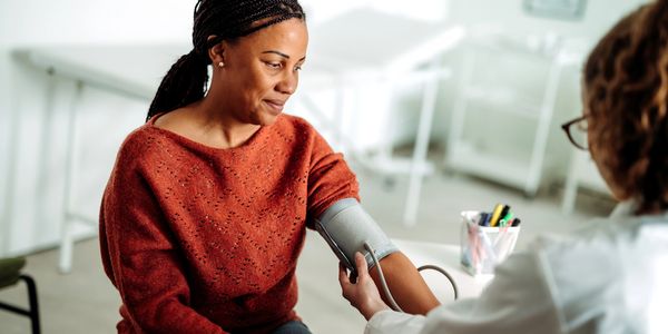 A woman getting her blood pressure checked by a healthcare professional.