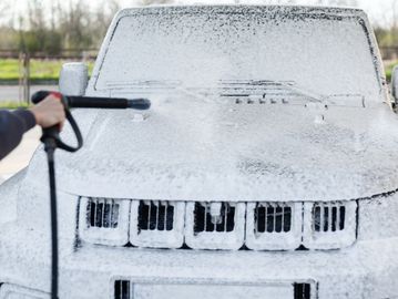 Car being cleaned with foam and pressure washer.