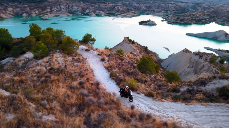 Adventurous motorcyclist exploring rugged arid landscape during golden hour, enjoying off road travel
