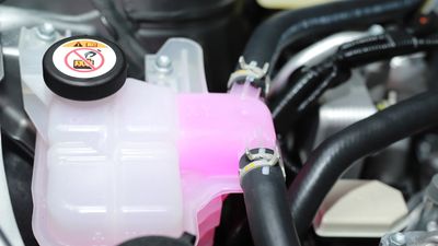 Close-up of a car's coolant reservoir with pink fluid.