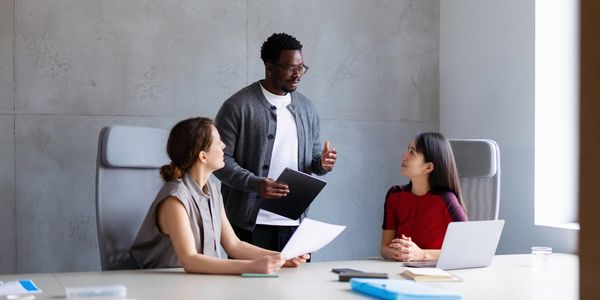 Trois collègues discutent dans une salle de réunion.