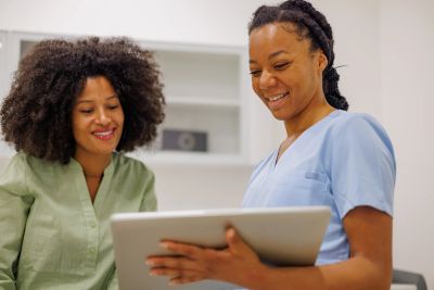 Two women smiling and looking at a tablet.
