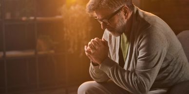 Man praying with eyes closed and hands clasped.