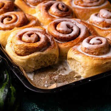 Freshly baked cinnamon rolls with icing in a baking tray.