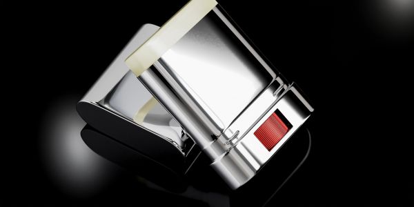 A sleek, modern metallic device with a red button on a reflective black surface.