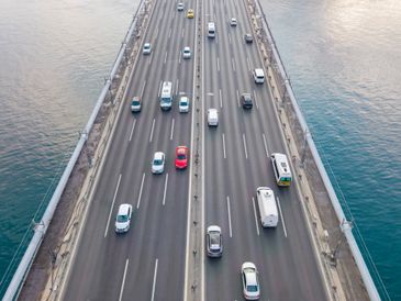 Aerial view of a busy multi-lane bridge over water with various vehicles.