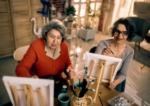 Two women painting together, enjoying an artistic activity.