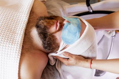 Man receiving a facial treatment with a mask on.