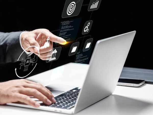 Hand interacting with AI icons and laptop.