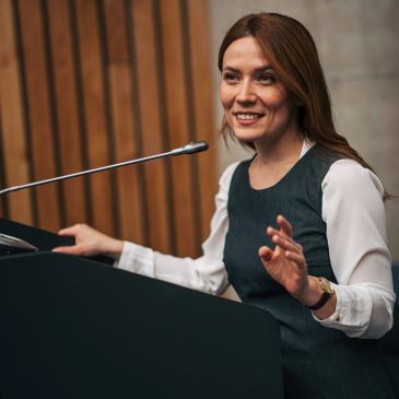 Woman speaking at a podium with microphone.
