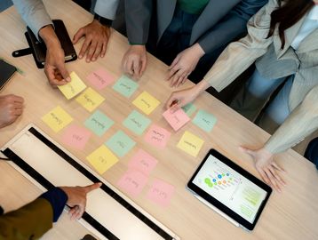 Team collaborating with sticky notes and tablet on table.