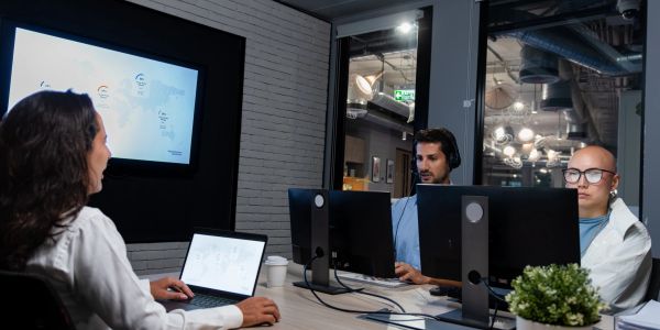 Réunion d'équipe dans un bureau avec des écrans d'ordinateur.