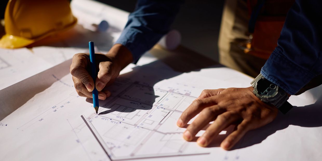 Person drawing on architectural blueprints.