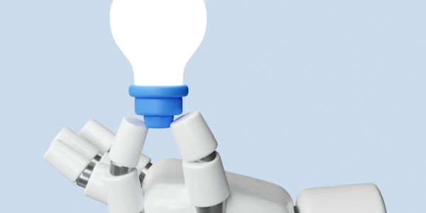 A robotic hand holding a glowing light bulb against a blue background.