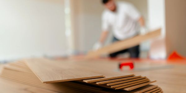 Person installing wooden flooring indoors.