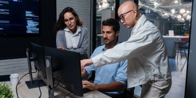 Three professionals collaborating at a computer in an office.
