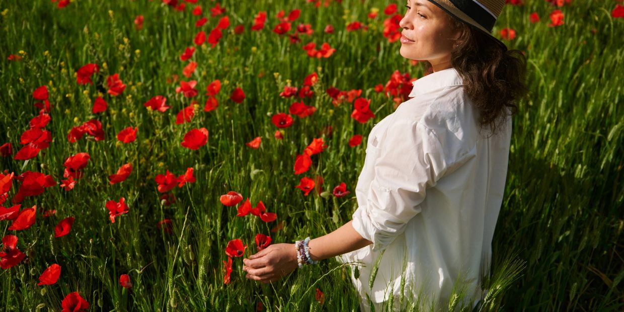 Woman in white shirt enjoying a red poppy field.