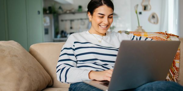 Woman smiling while using a laptop at home.