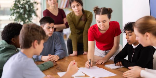Teenagers collaborating around a table on a project.