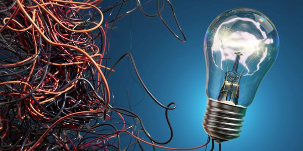 Tangled wires connected to a glowing light bulb.