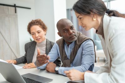 Three colleagues discussing work at a laptop.